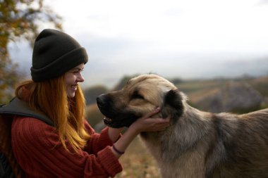 Açık havada gezen bir köpeğin yanında neşeli bir kadın.