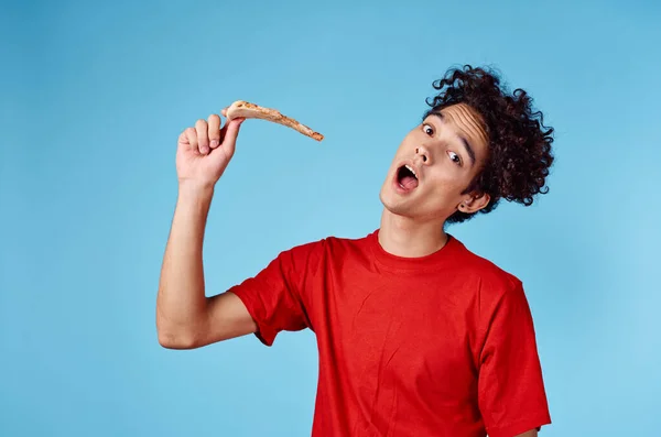 Glücklicher Kerl mit einem Stück Pizza auf blauem Hintergrund lockiges Haar Emotionen abgeschnitten Ansicht — Stockfoto