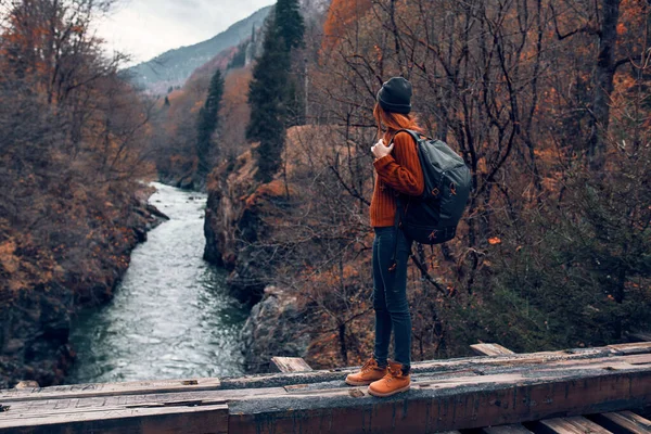 Femme se tient sur un pont sur une rivière dans les montagnes Voyage en forêt d'automne — Photo