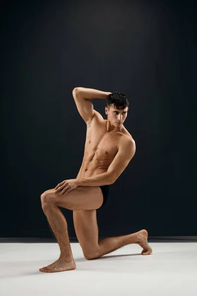 Man with a pumped-up naked body posing on his knee — Stock Photo, Image