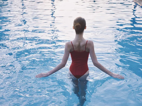 Mulher sexy corre suas mãos sobre a água transparente da piscina — Fotografia de Stock