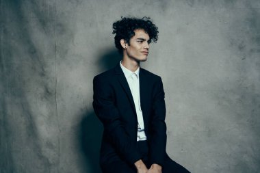 Takım elbiseli, kıvırcık saçlı, modern moda bir sandalyede oturan iş adamı.