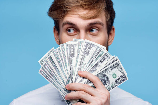 man holding money close-up wealth success blue background