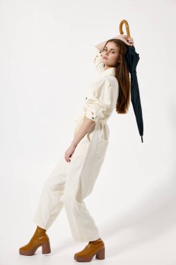 Beyaz takım elbiseli çekici bir kadın kafasının arkasında bir şemsiye tutuyor.