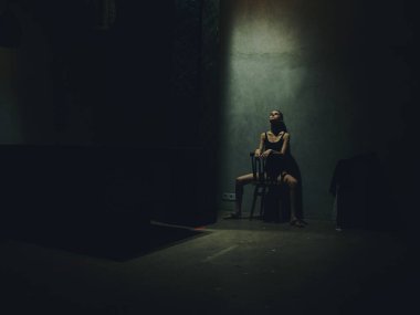 Sandalyeye yaslanmış, duvarlara yaslanmış bir kadın. Yalnızlık depresyon çatışması.