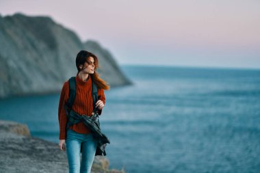 Sırt çantalı, kot pantolonlu bir kadın dağ manzarası modeli.