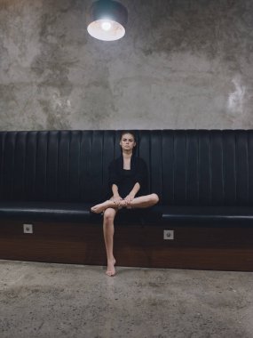 Takım elbiseli zarif bir kadın koltukta çıplak ayakla oturuyor. İçeride havaalanı tasarımını bekliyor.