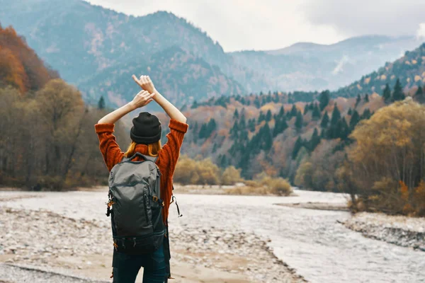 Gelukkig vrouw reist in de buurt van de berg rivier in de natuur in de herfst en gebaren met haar handen — Stockfoto