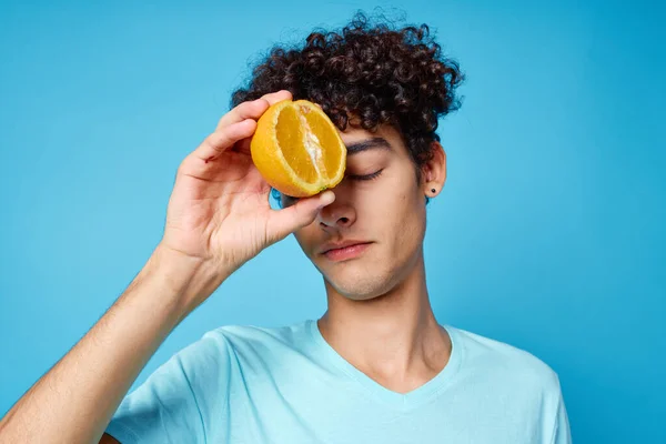 Hombre con pelo rizado sosteniendo naranjas fruta fondo azul — Foto de Stock