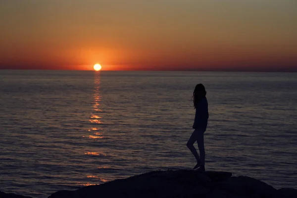 Puesta de sol en las montañas junto al mar y una silueta femenina en la playa — Foto de Stock