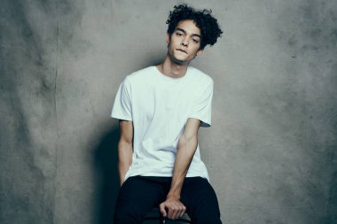 Sandalye stüdyosunda oturan kıvırcık saçlı yakışıklı adam.