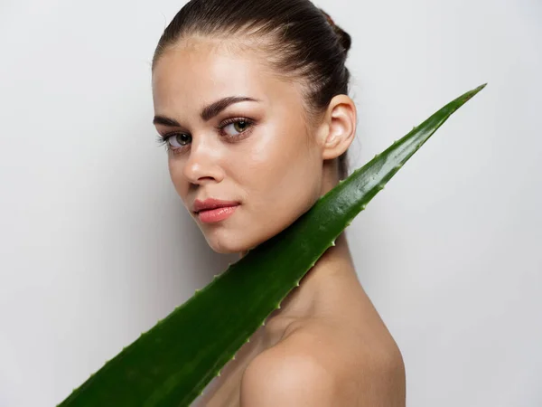 Retrato de uma mulher com ombros nus e folha de aloés verde pele clara cosmetologia maquiagem vista lateral — Fotografia de Stock