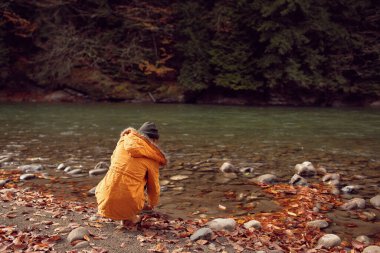 Nehir kıyısında yürüyen kadın, düşmüş doğa dağlarını terk ediyor.