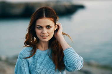 Elinde saç tutan gülümseyen kadın doğa turizmi sallıyor.