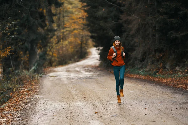 Donna con uno zaino in piena crescita cammina lungo la strada nel bosco — Foto Stock