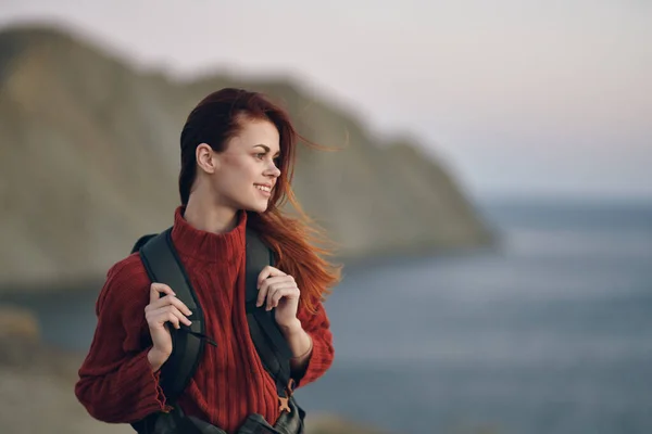 Donna escursionista tiene uno zaino sulle spalle e guardare il mare dal lato delle montagne sullo sfondo — Foto Stock