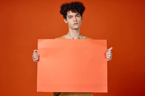 Érzelmi srác göndör haj sziget kezében reklám piros háttér — Stock Fotó