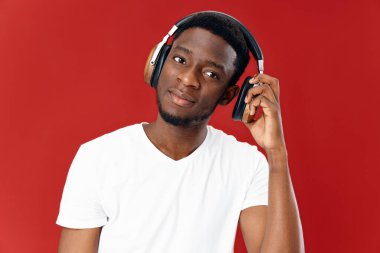 Kulaklık takan beyaz tişörtlü adam müzik teknolojisi yaşam tarzı kırmızı arka plan