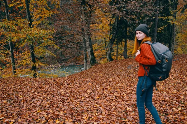 Reiziger met rugzak in de herfst bos en hoed trui jeans gevallen bladeren meer bomen — Stockfoto