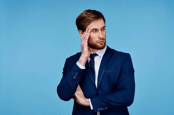 Hombre de negocios en un traje sostiene su mano cerca de su cabeza disgusto fondo azul — Foto de Stock