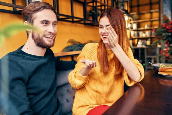 Homem bonito e mulher feliz em suéter estão sentados a uma mesa em um café conversando quarto interior — Fotografia de Stock