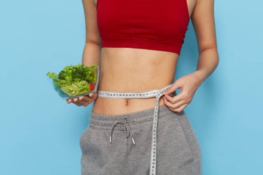 Sıska kadın bir tabağın boyutunu salata diyeti ile ölçer.