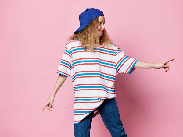 Flicka i fashionabla kläder i en blå cap rosa bakgrund modern stil — Stockfoto