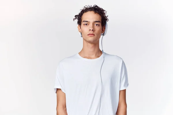 Adolescente en una camiseta escuchando música en los auriculares en un fondo de luz recortado ver de cerca — Foto de Stock