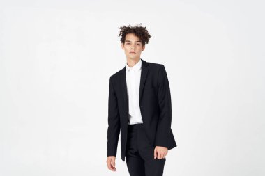 Klasik takım elbiseli genç adam açık arkaplanda kıvırcık saçlı, kırpık manzaralı.