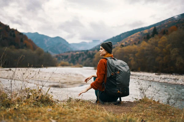 Žena turistka na březích řeky na podzim a hory ve vzdálenosti mraky počasí příroda — Stock fotografie