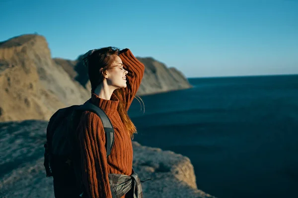 pretty woman in a sweater with a backpack near the sea in nature