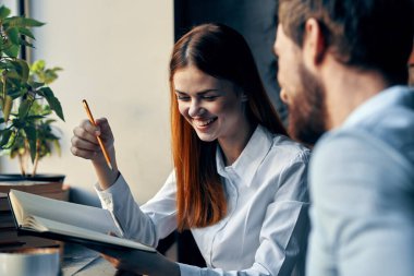 İş adamı ve kadın masadaki iletişim ofisinde oturuyor.