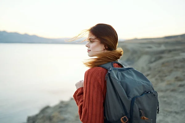Donna viaggia in montagna nella natura vicino al mare con uno zaino sulla schiena — Foto Stock