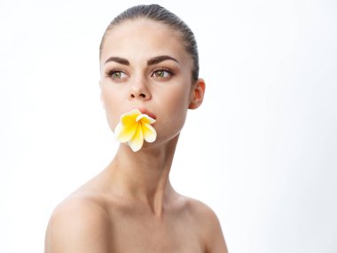 Dişinde sarı bir çiçek olan bir kadının portresi.