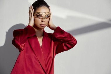 Yüzünde süs olan kadın kulaklarını ve ipek ceketini kapatmış.