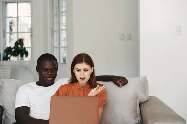 Homme et femme à la maison sur le canapé devant la communication ordinateur portable — Photo