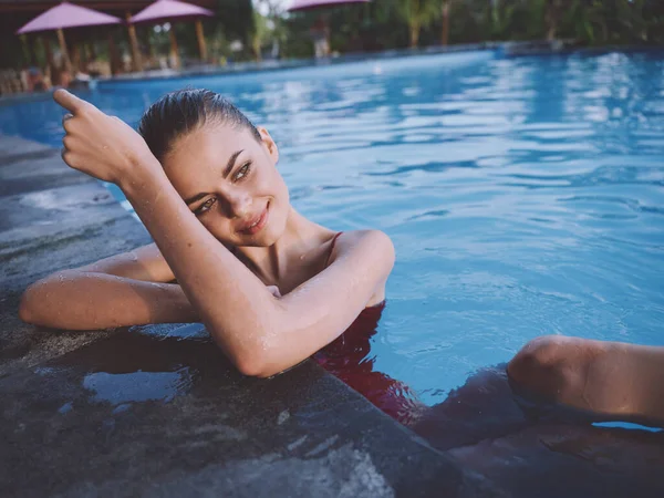 Bela mulher com cabelo molhado está se apoiando no azulejo da piscina e apontando para o lado Espaço Copiar — Fotografia de Stock