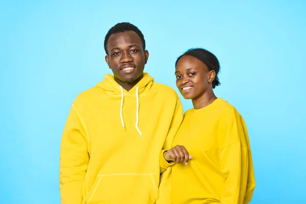 Homme gai et femme d'apparence africaine dans les pulls jaunes studio de mode fond bleu — Photo