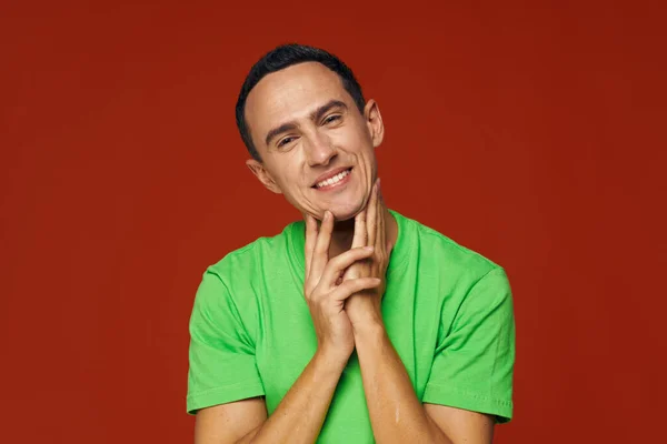 Веселый человек в зеленой футболке улыбка эмоции студии красный фон — стоковое фото