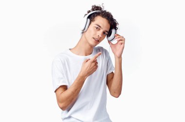 Kulaklık takan yeni teknolojili beyaz tişört giyen bir genç. Arka plan müzik modeli.