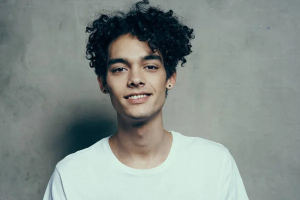 Glad tonåring i vit t-shirt lockigt hår skrattar leende beige bakgrund fotografering studio — Stockfoto