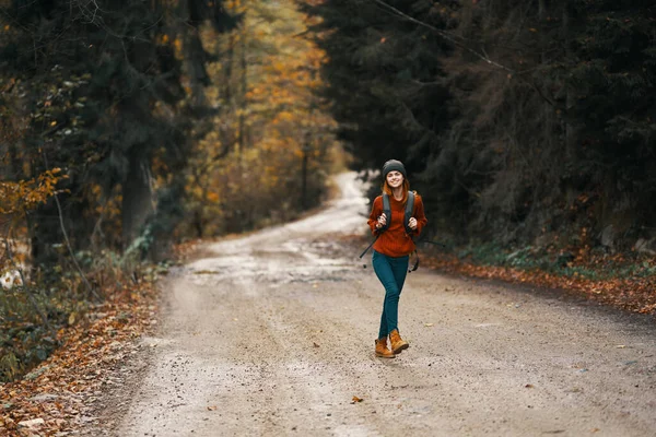 Donna energica che corre lungo la strada con lo zaino nella foresta autunnale — Foto Stock