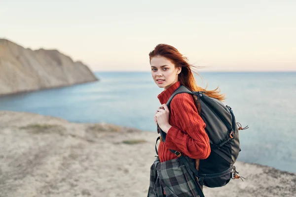 Bella donna con uno zaino in montagna maglione rosso modello acconciatura oceano mare — Foto Stock