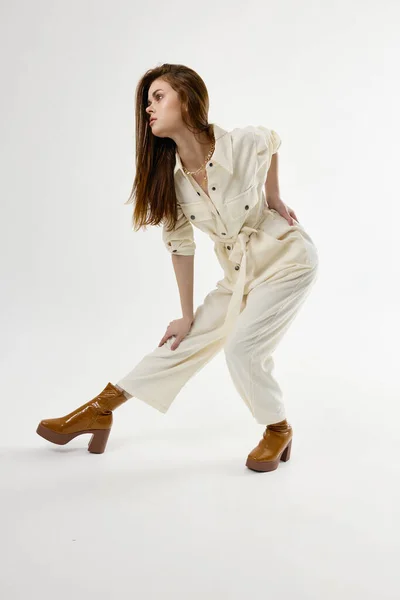 Mulher atraente botas de moda macacão branco dobrado para a frente — Fotografia de Stock