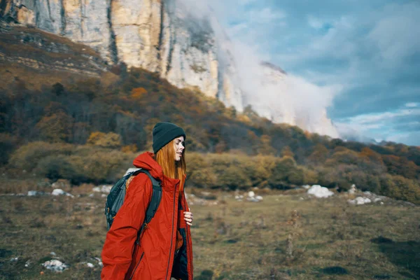 Mujer en chaquetas gorras con una mochila en la espalda camina en el otoño en las montañas y en la naturaleza — Foto de Stock