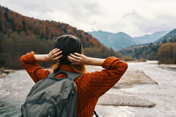 강 근처의 자연 속 의산 속을 여행하는 여자는 손을 머리 뒤로 잡고 여행 한다 — 스톡 사진