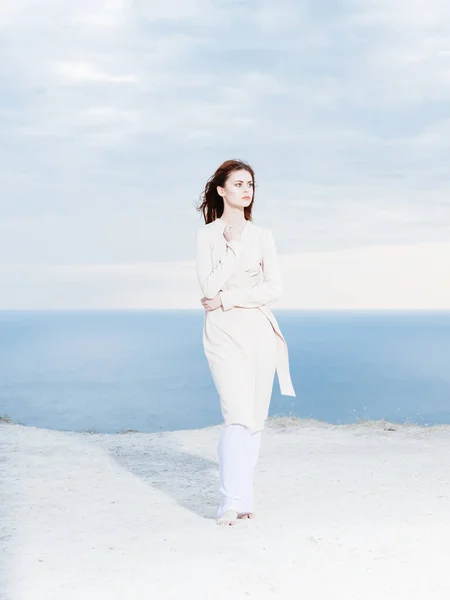 Mulher em roupas leves pelo oceano e céu azul no fundo — Fotografia de Stock