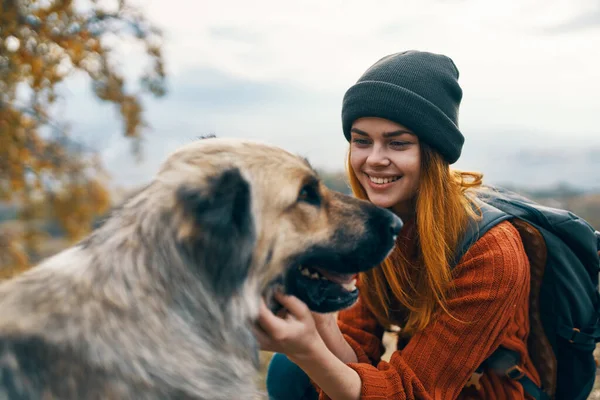 Весела жінка турист пестить собаку на відкритому повітрі ландшафтний відпочинок — стокове фото