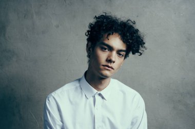 Beyaz tişörtlü kıvırcık saçlı, kıvırcık saçlı, duyguları olan bir adam.