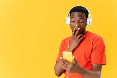 Kulaklıklı bir adam elinde telefonla müzik dinliyor. Şaşkın şaşkın bakıyor.